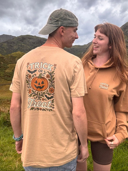 Beige organic cotton Halloween T-shirt with a large “Trick or Treat” pumpkin jack-o’-lantern design surrounded by bats and autumn florals on the back, and a smaller matching logo on the front chest. Sustainably made and nature-inspired, with a cute festive pumpkin design. 🎃🍂 Made by Aurora's Destination and photgraphed in The Lake District - Lake Windermere 